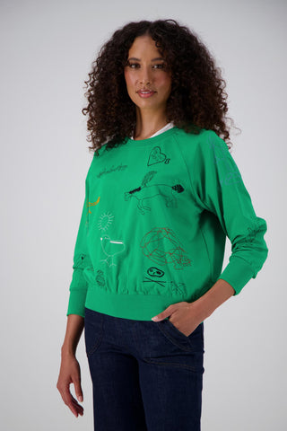 Olga de Polga Green Montage sweatshirt in a cotton tence blend. The sweatshirt has abstract embroidered motifs. Ribbing at the neckline, cuffs and hem add durability to the sweatshirt.  Side front on model