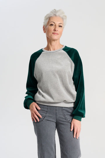 Olga de Polga Green Odessa Sweatshirt. The Odessa Sweatshirt combines comfort and style in a two-tone colour design. Crafted from soft cotton velour, it’s perfect for mild weather and busy days when versatility and comfort are key. Front view on model.