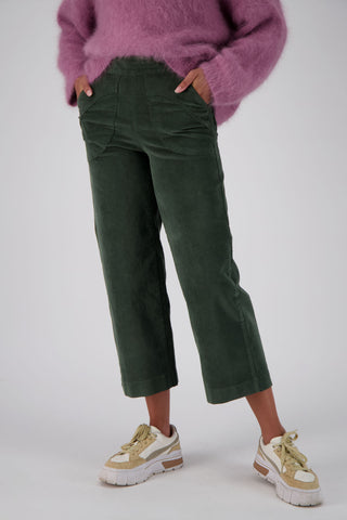 Olga de Polga Olive Green Fine Cord Peggy Pants. Cropped ankle length and large patch pockets, wit a side zip fastening. Our best selling pants.  Front close up view on model