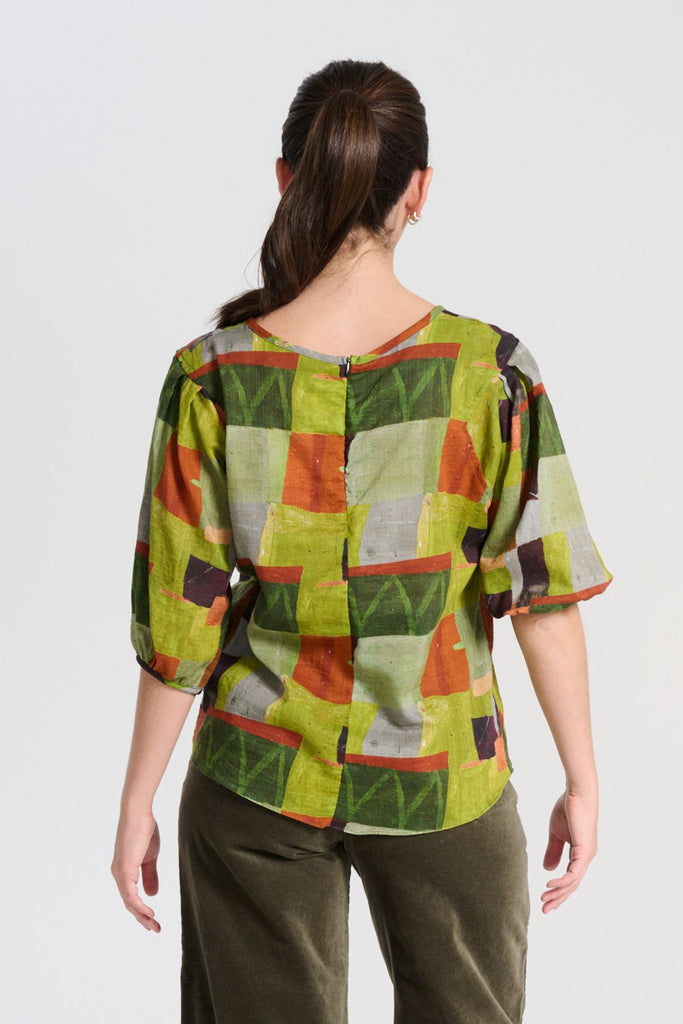 Olga de Polga classic blouse in green Kismet Sage printed cotton seersucker. The blouse features a beautifully detailed lantern sleeve with a drop shoulder and delicate pleating on the shoulder and cuff. It also has a wide boat neckline and invisible zip fastening at the back. Back view on model