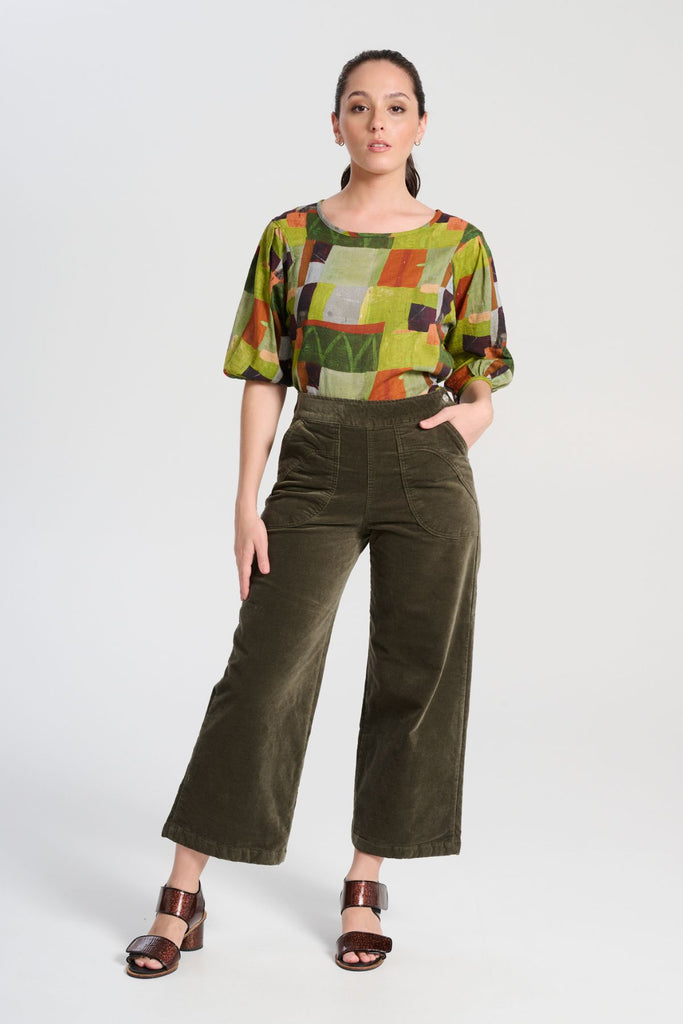 Olga de Polga classic blouse in green Kismet Sage printed cotton seersucker. The blouse features a beautifully detailed lantern sleeve with a drop shoulder and delicate pleating on the shoulder and cuff. It also has a wide boat neckline and invisible zip fastening at the back. Front full length view on model