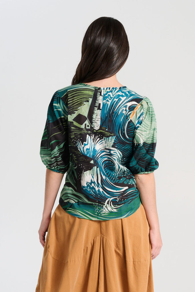 Olga de Polga green Isla Tide blouse in printed cotton seersucker. Our signature Olga Blouse is a feminine staple that can take you from work to weekend with ease. The blouse features a beautifully detailed lantern sleeve with a drop shoulder and delicate pleating on the shoulder and cuff. It also has a wide boat neckline and invisible zip fastening at the back. Back view on model.