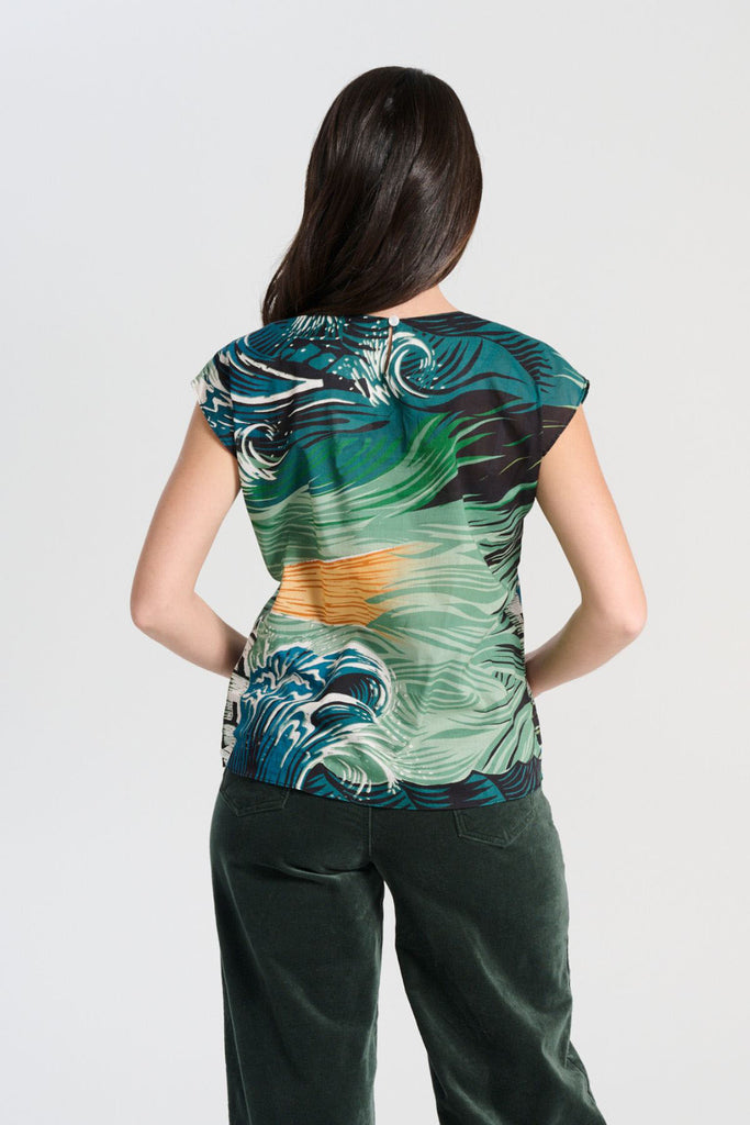 Olga de Polga Isla tee in Tide green printed cotton voile. With cap sleeves, a round neckline with a button fastening at the back neck, tapering in at the waist and finishing at the hip, this tee is perfect for all occasions. Back view on model