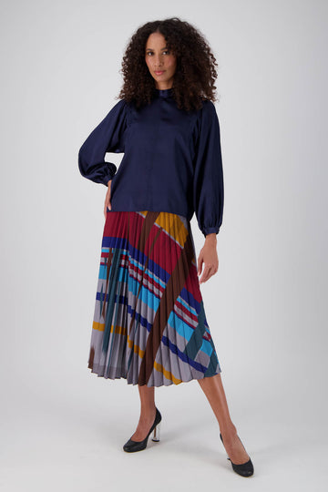 Olga de Polga pleated skirt in our Crossroads Primary printed recycled polyester. Elasticated waistband. Midi length. Front full length view on model