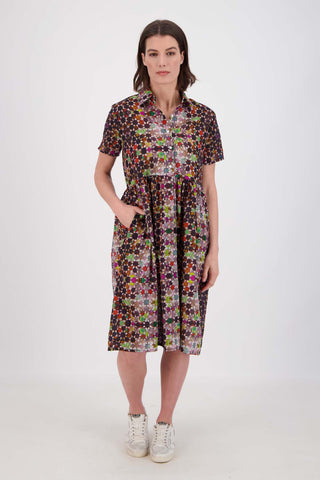 Olga de Polga Grey Kaleidoscope printed Villa dress in long length. Shirt dress with a button front. Finishes just below the knee. 100% Cotton. Front view on model with hand in pocket.