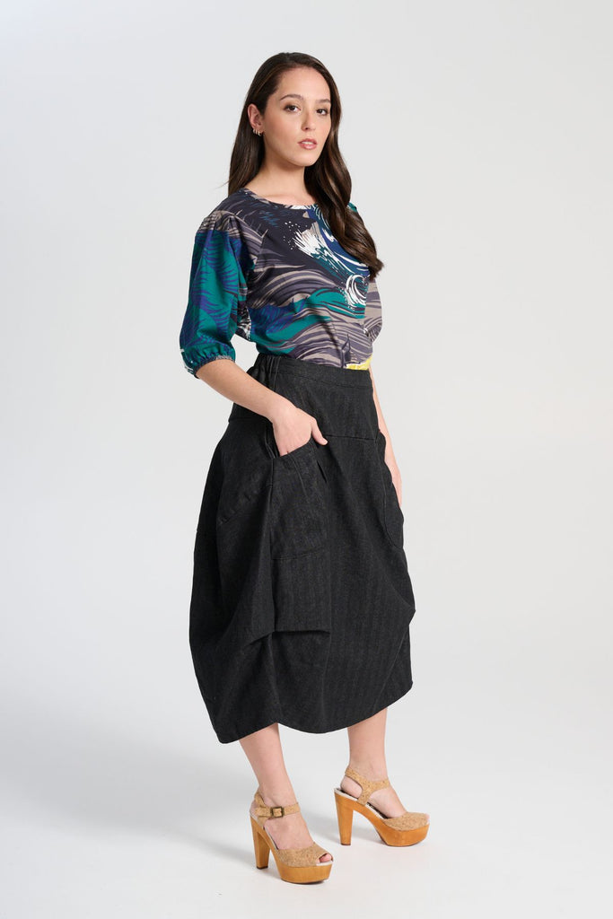 Olga de Polga classic blouse in the Storm Isla printed cotton. The blouse features a beautifully detailed lantern sleeve with a drop shoulder and delicate pleating on the shoulder and cuff. It also has a wide boat neckline and invisible zip fastening at the back. Side view on model