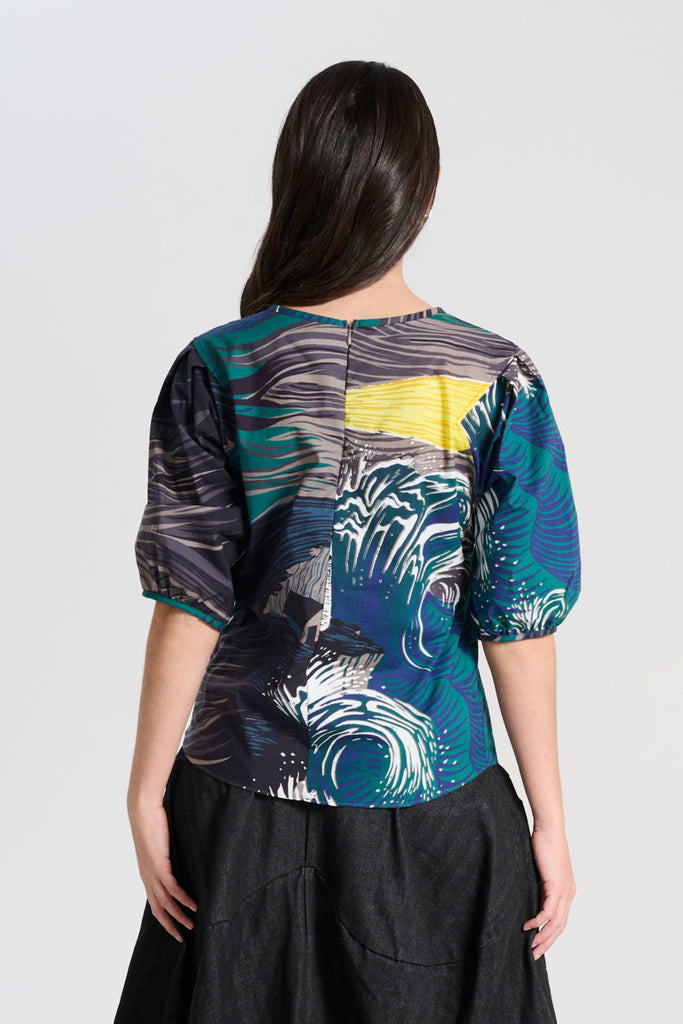 Olga de Polga classic blouse in the Storm Isla printed cotton. The blouse features a beautifully detailed lantern sleeve with a drop shoulder and delicate pleating on the shoulder and cuff. It also has a wide boat neckline and invisible zip fastening at the back. Back view on model
