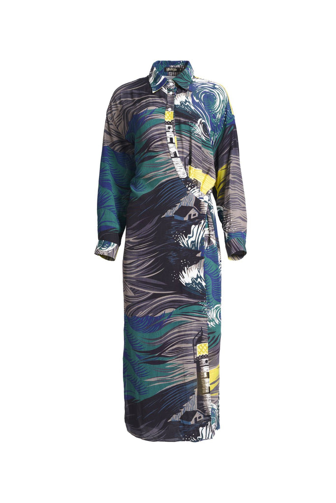 Olga de Polga Fluido wrap shirt dress. Printed Viscose. The Isla print captures the power of nature, with crashing waves and a guiding lighthouse. Deep blues, stormy greens, and yellow accents evoke hope and direction through turbulent times, reflecting the challenges of life and the human drive to navigate the unknown. Front view