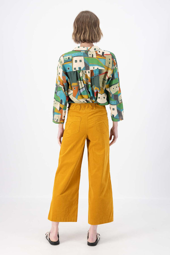 Olga de Polga Peggy Pants in Mustard Yellow fine cotton cord. Cropped length, large front patch pockets, elasticated waistband, side zip fastening. Back view on model.