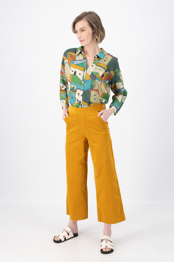 Olga de Polga Peggy Pants in Mustard Yellow fine cotton cord. Cropped length, large front patch pockets, elasticated waistband, side zip fastening. Front view on model.