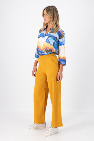 Olga de Polga Peggy Pants Long Lino in linen. Featuring a flattering high waist with an elasticated back, these pants provide all-day comfort while maintaining a sleek, streamlined look. With their stretchy wide-leg fit, flat front, and full-length silhouette, they effortlessly elevate any outfit. Side view on model.