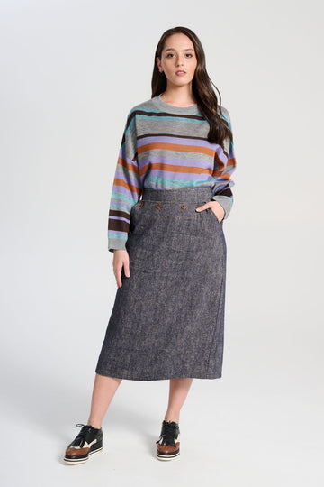 Olga de Polga Navy Hepburn Haven skirt in a wool/linen fabric blend. Featuring a unique button detail at the waist that forms a flattering pocket shape, this skirt adds personality to any outfit. With an elasticated back waist for comfort, it finishes just below the knee and has a stylish back split for ease of movement. Front view on model.