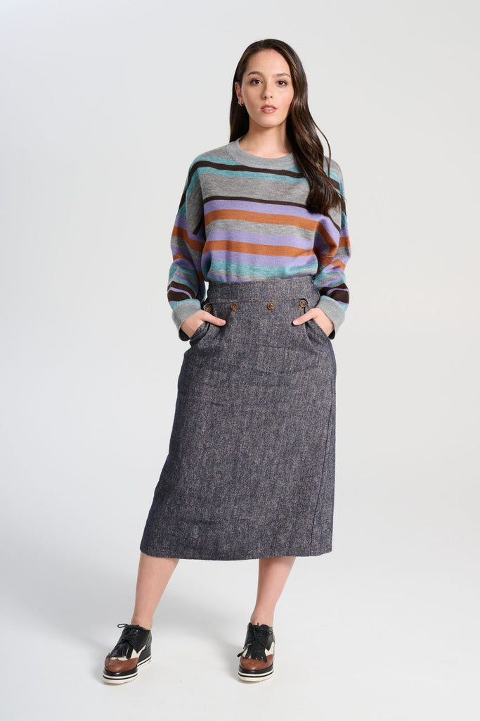 Olga de Polga Navy Hepburn Haven skirt in a wool/linen fabric blend. Featuring a unique button detail at the waist that forms a flattering pocket shape, this skirt adds personality to any outfit. With an elasticated back waist for comfort, it finishes just below the knee and has a stylish back split for ease of movement.  Front full length view on model.