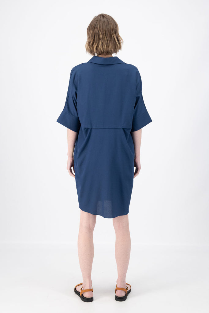 Olga de Polga Marianna Estilo dress in Navy. Shirt dress with bat-wing sleeves and a collar with short button opening at the front. Finishes above the kneed depending on height. Back view on model.