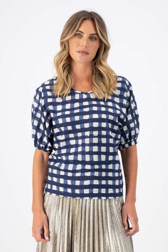 Olga de Polga Camisa blouse in the Rosa Navy print. Printed woven cotton. 100% Cotton. Reversible top to have either a boatneck or a soft V-neckline. Half sleeves with elasticated cuff. Front view on model.