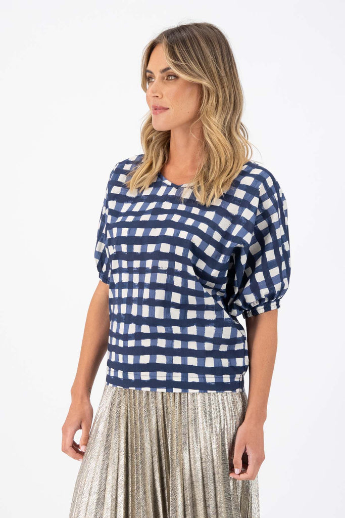 Olga de Polga Camisa blouse in the Rosa Navy print. Printed woven cotton. 100% Cotton. Reversible top to have either a boatneck or a soft V-neckline. Half sleeves with elasticated cuff. Side view on model.