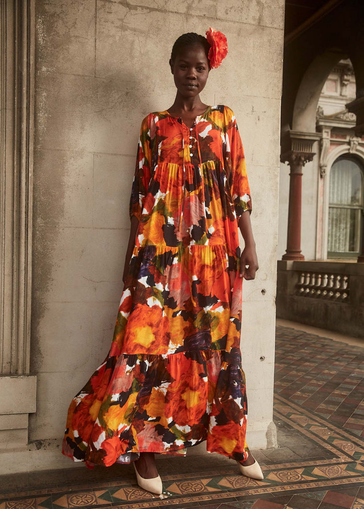 Olga de Polga Fiorella Orange Olivia Dress in viscose crepe.Maxi dress with half sleeves and buttons at the front down to the waist seam. Round neckline. A-line tiered skirt in a drapey fabric. Full front view on model