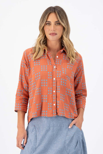 Olga de Polga Network printed cotton shirt in orange with a button down front and collar. 3/4 length sleeves with a foldable sleeve and button fastening. Front view on model.