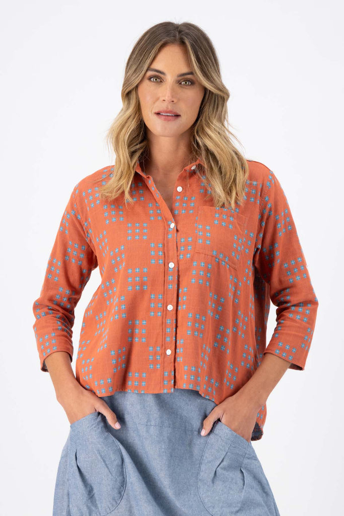 Olga de Polga Network printed cotton shirt in orange with a button down front and collar. 3/4 length sleeves with a foldable sleeve and button fastening. Front  close-up view on model.