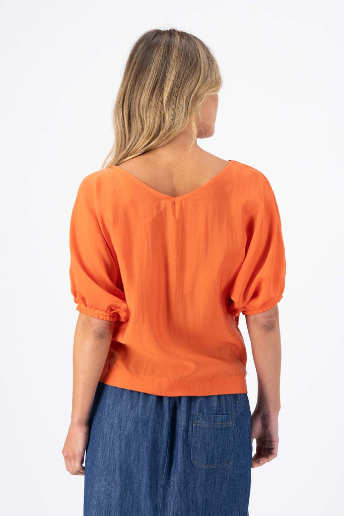 Olga de Polga Camisa Blouse in Orange Skyscraper Tencel. Reversible top with a soft v-neck on one side and a boat neck on the other. Back view on model.