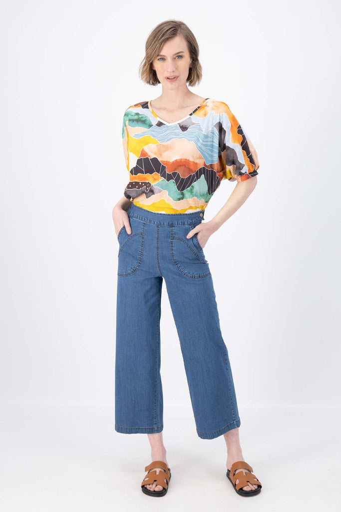 Olga de Polga Orange Vista printed cotton Camisa. Blouse. Reversible top with a soft v-neck on one side and a boat-neck on the other.
Half sleeves, with a bat-wing shape, and tapers in at the hips. Front full length view on model.