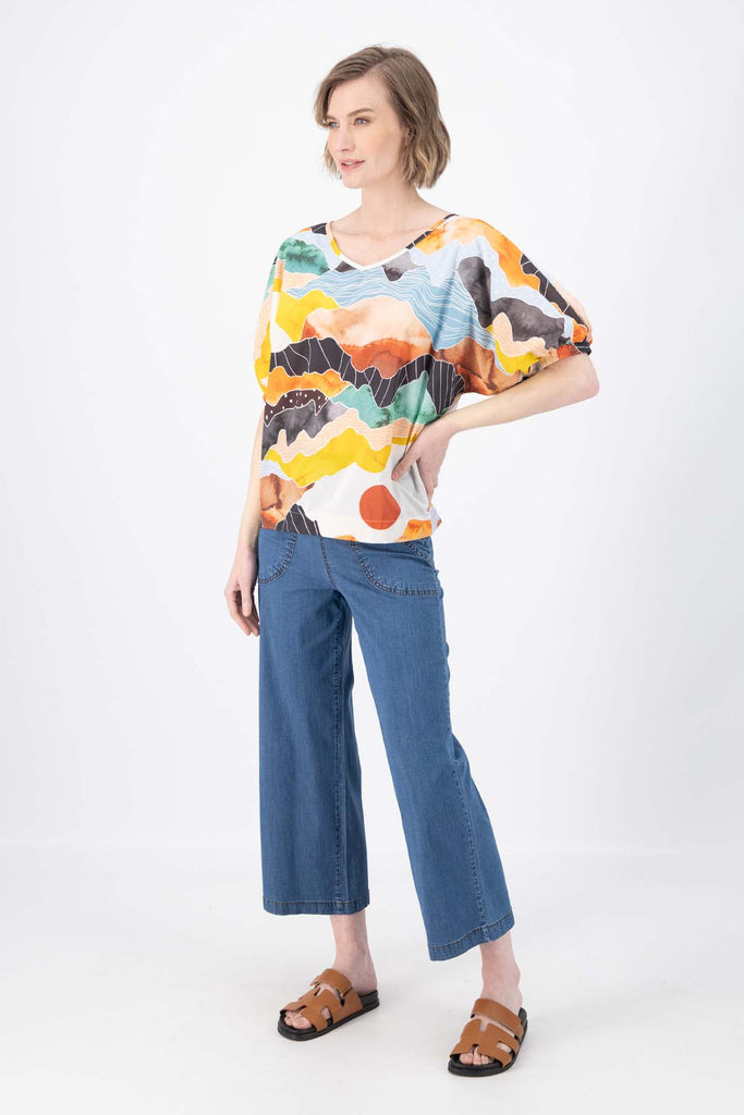 Olga de Polga Orange Vista printed cotton Camisa. Blouse. Reversible top with a soft v-neck on one side and a boat-neck on the other.
Half sleeves, with a bat-wing shape, and tapers in at the hips. Side front view on model.