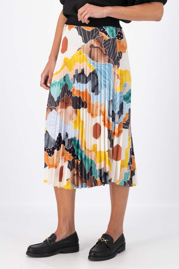 Olga de Polga pleated skirt in the Orange Vista print. Elasticated waistband. Vibrant unique print. Midi length. Side view on model.