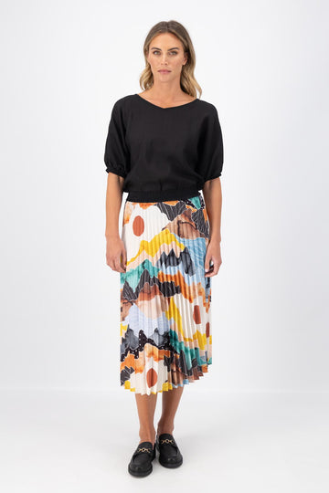 Olga de Polga pleated skirt in the Orange Vista print. Elasticated waistband. Vibrant unique print. Midi length. Front full view on model.