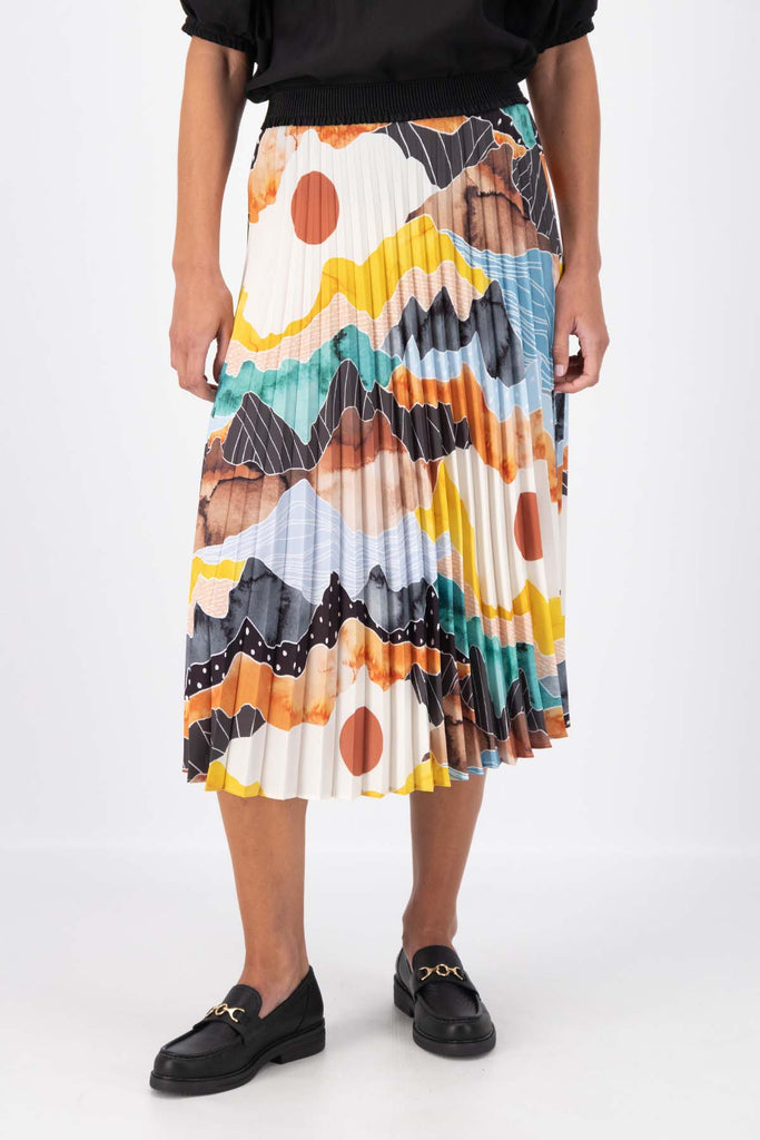 Olga de Polga pleated skirt in the Orange Vista print. Elasticated waistband. Vibrant unique print. Midi length. Front view on model.