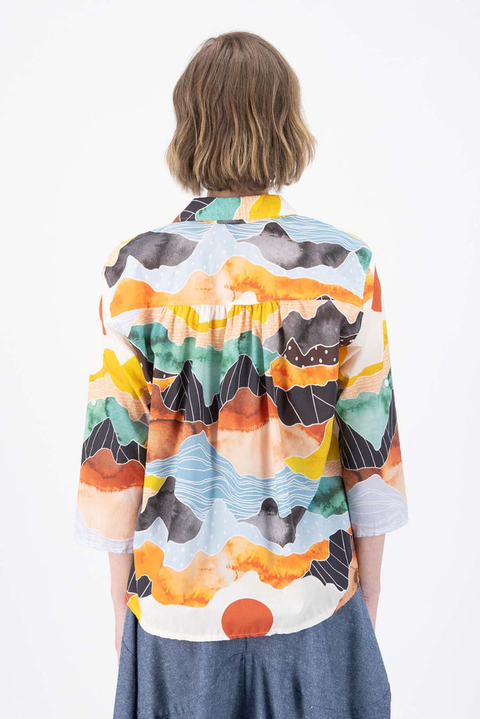 Olga de Polga Orange Vista printed shirt in 100% Cotton. Collar and button down front. 3/4 sleeves. Hip length. Finishes longer at the back. Back view on model.