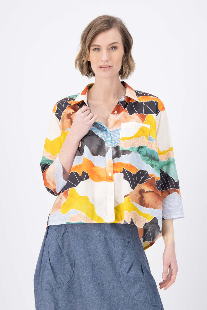 Olga de Polga Orange Vista printed shirt in 100% Cotton. Collar and button down front. 3/4 sleeves. Hip length. Finishes longer at the back. Front view on model.