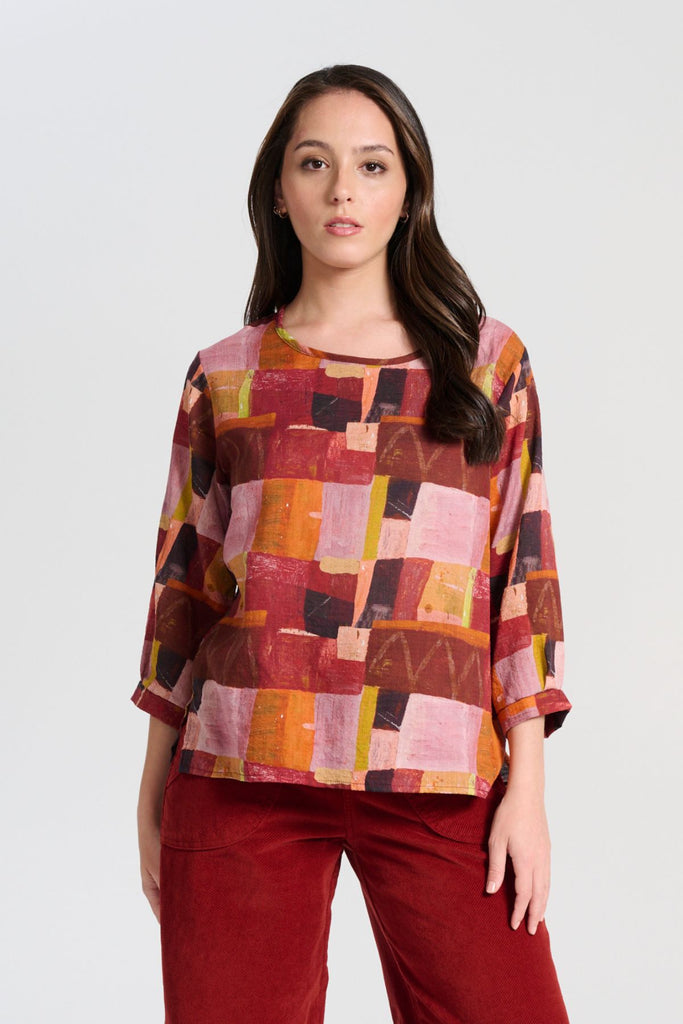 Olga de Polga Chemise blouse in cotton seersucker. In the printed Kismet Blush print with reds, oranges and pinks from the AW25 Odyssey collection. 3/4 length sleeves, round neckline, back neck button opening. Front view on model