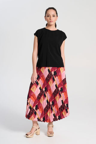 Olga de Polga classic pleated skirt in printed Kismet Blush Pink. Midi length. Fully elasticated waistband. Front view on model with top untucked.