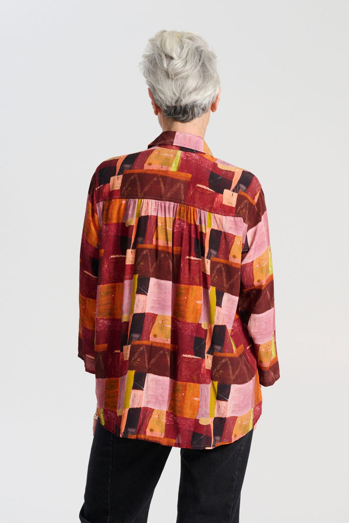 Olga de Polga classic shirt in printed viscose. Kismet Blush Print. Button down front, 3/4 sleeves and a front patch pocket. Print has colours of red, pink, burgundy and accents of yellow and orange. Back close up view