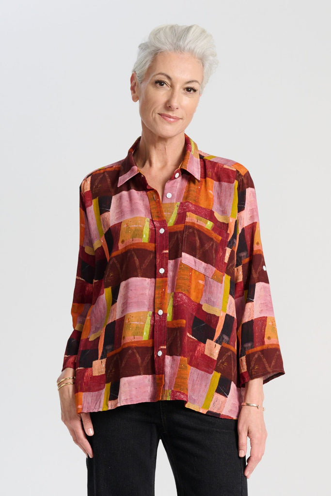 Olga de Polga classic shirt in printed viscose. Kismet Blush Print. Button down front, 3/4 sleeves and a front patch pocket. Print has colours of red, pink, burgundy and accents of yellow and orange. Front view on model.