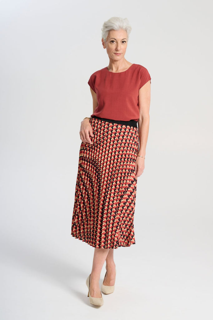 Olga de Polga printed pleat skirt in the Seraph Sunset print. Shades of orange, red and black. Fully elasticated waistband. Front view on model. 