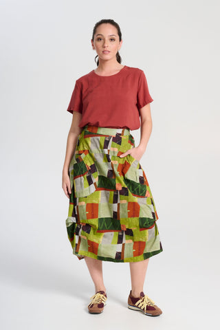 Olga de Polga Rhea Top in Rust. 100% Tencel. Round neckline and short sleeves. A boxy t-shirt shape in a soft silky Tencel fabric. Front full length view with the top tucked into a skirt.