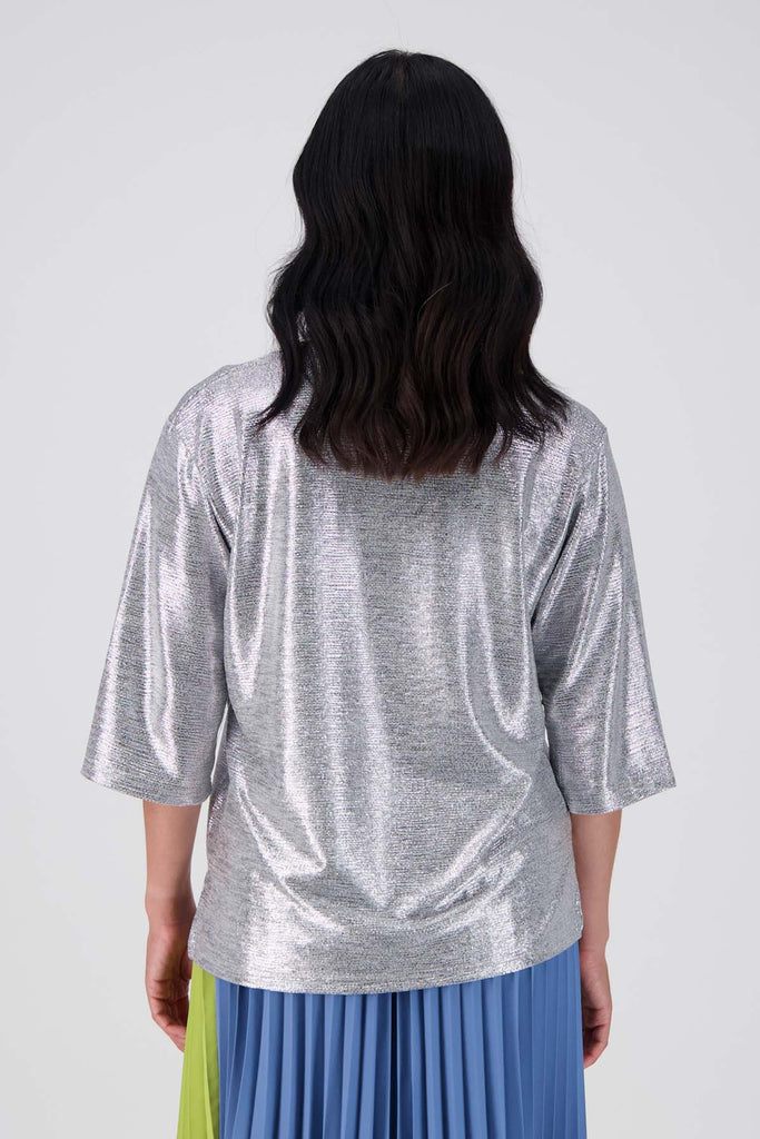 Olga de Polga silver prosecco top. Crafted from a soft, woven metallic fabrication, this top is comfortable enough to wear all day and night. With a relaxed fit, scoop neckline, and 3/4 length sleeves, your everyday t-shirt now boasts a lustrous twist.  Back view on model