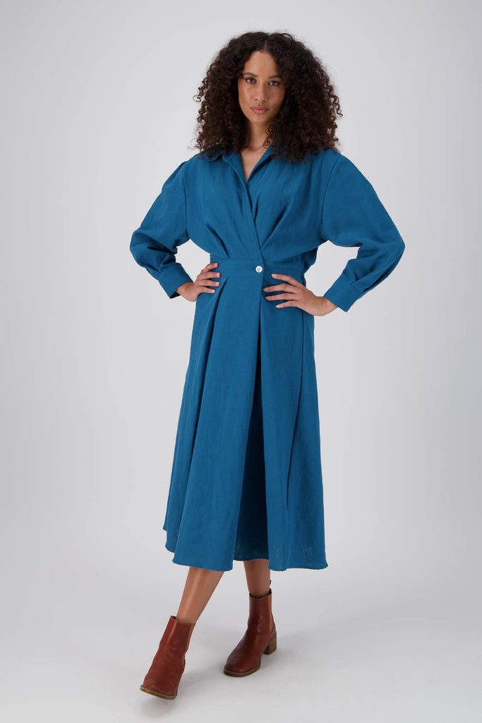 Olga de Polga Teal Parisian Estate dress in 100% Linen. Straight silhouette with a cinched waistband. Two buttons on the front allow the waistband to be adjusted. Elastic waistband at the back. Front full length view on model