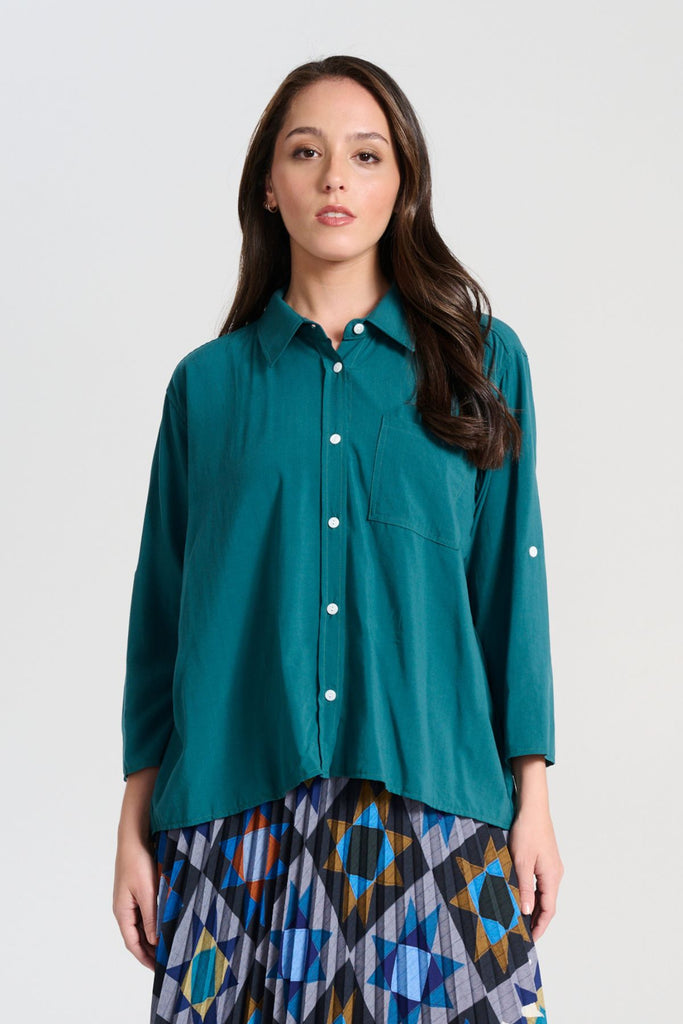 Olga de Polga Teal Rhea shirt in 100% soft Tencel. The front of the shirt sits at the waist while the back falls to the hips for a lovely drape. Perfect for leaving loose over pants or for tucking into any bottoms. Front view on model
