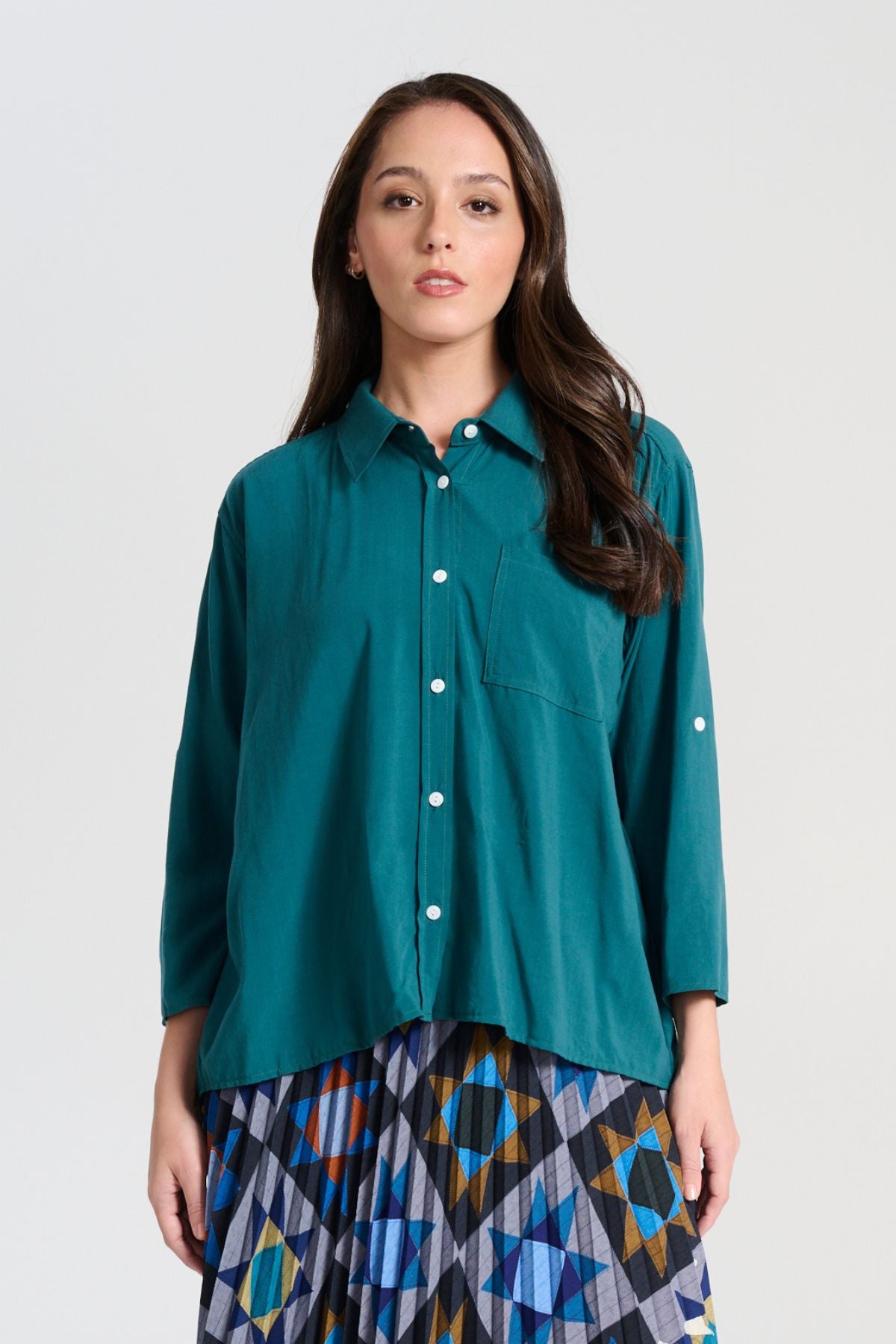 Olga de Polga Teal Rhea shirt in 100% soft Tencel. The front of the shirt sits at the waist while the back falls to the hips for a lovely drape. Perfect for leaving loose over pants or for tucking into any bottoms. Front view on model