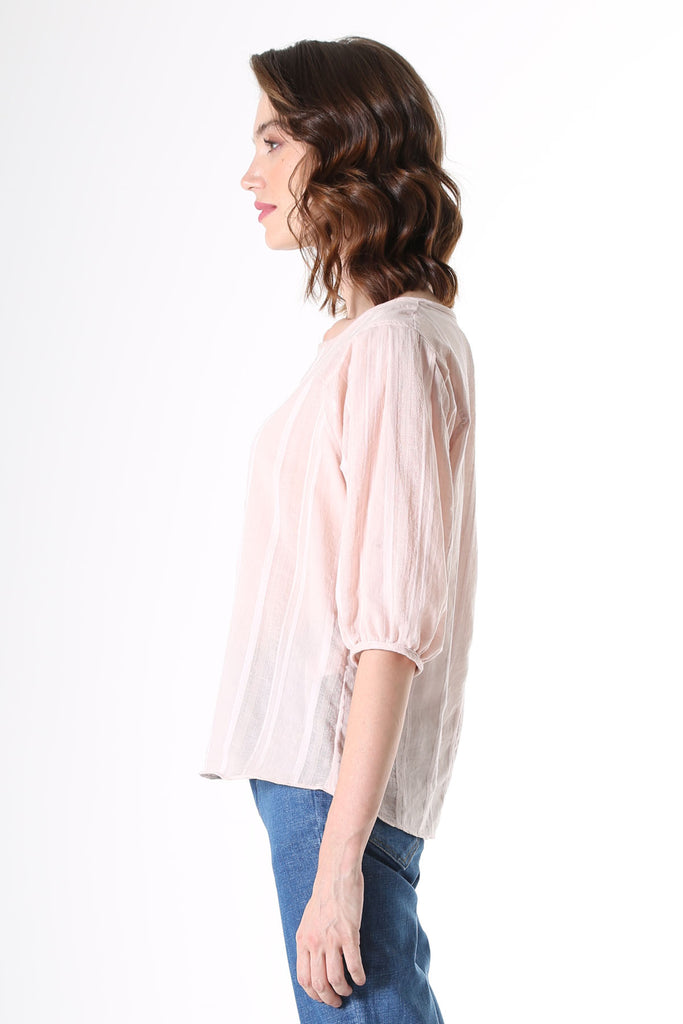 Olga de Polga Blouse in Avenida textured cotton pale pink. the blouse features a beautifully detailed lantern sleeve with a drop shoulder and delicate pleating on the shoulder and cuff. It also has a wide boat neckline and invisible zip fastening at the back.