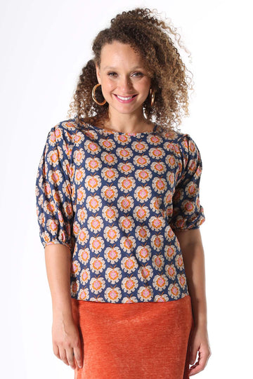 Olga de Polga blouse in the Olga-de-lis Print. Fun vintage inspired block print in navy, with motifs in beige, mustard and hot pink. Made in our signature light-weight cotton/rayon fabric with a soft floaty drape. With a slim cut that narrows slightly at the waist, the blouse features a beautifully detailed lantern sleeve with a drop shoulder and delicate pleating on the shoulder and cuff. It also has a wide boat neckline and invisible zip fastening at the back.