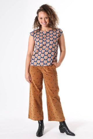 Olga de Polga printed tee Olga-de-lis.  Our signature Olga Tee is a slim cut, fitted at the shoulders and waist, with cap sleeves and a round neck, and a button fastening at the back. Fun vintage inspired block print in navy, with motifs in beige, mustard and hot pink. Made in our signature light-weight cotton/rayon fabric with a soft floaty drape. 