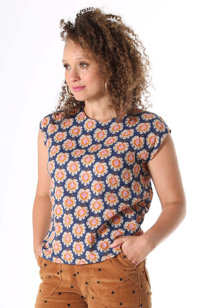 Olga de Polga printed tee Olga-de-lis.  Our signature Olga Tee is a slim cut, fitted at the shoulders and waist, with cap sleeves and a round neck, and a button fastening at the back. Fun vintage inspired block print in navy, with motifs in beige, mustard and hot pink. Made in our signature light-weight cotton/rayon fabric with a soft floaty drape. 
