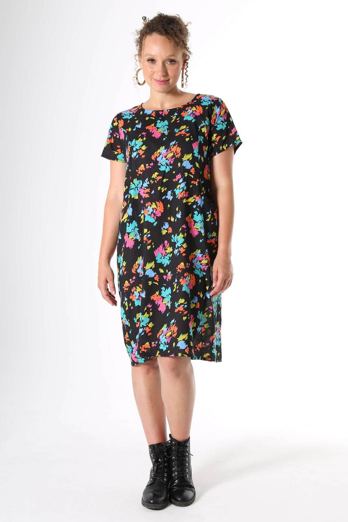 Olga de Polga knee length shift dress with short sleeves and pockets. Printed in Deep black with splashes of neon pink, orange, yellow and aqua. Soft, light-weight cotton/rayon fabric with a floaty drape.  